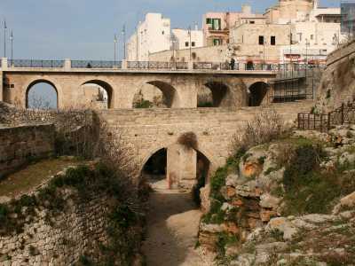 Il viottolo a un certo punto va in salita e ci porta in un punto in cui, girandoci, possiamo avere una visione d�insieme dei due ponti con alle spalle le case del centro storico di Polignano a picco sul mare